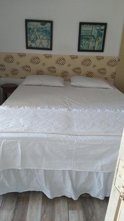 ein großes weißes Bett mit zwei Kissen darauf in der Unterkunft Hospedaria Ilhéus 03 in Ilhéus
