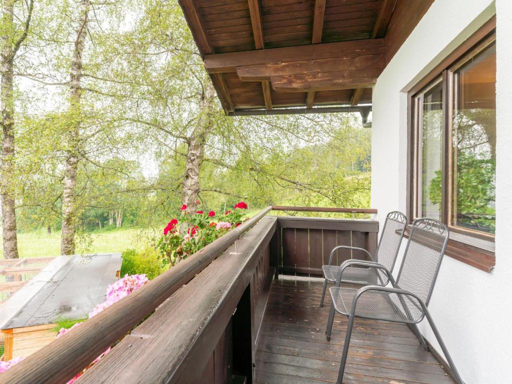 um alpendre com duas cadeiras, uma janela e flores em Katharina em Brixen im Thale