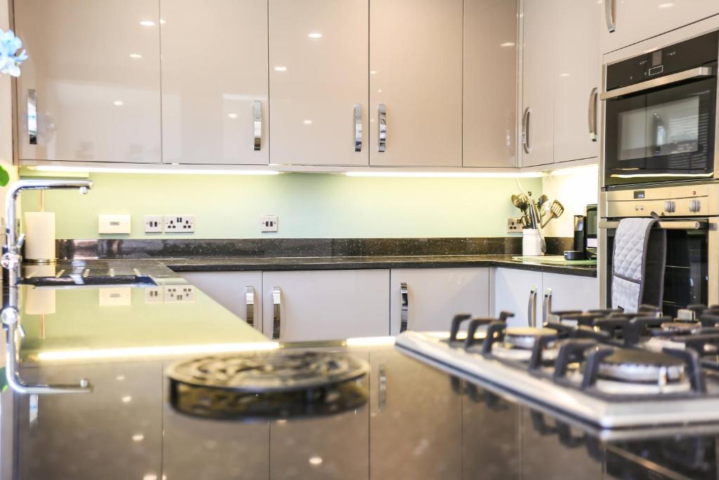 a kitchen with white cabinets and a stove top oven at Seascape - 4 bed home in Bracklesham Bay in Chichester