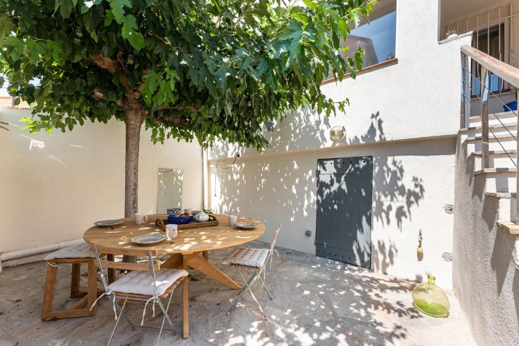 a wooden table and chairs on a patio with a tree at A LA CALANQUE - Jolie Maison en bord de mer in Marseille