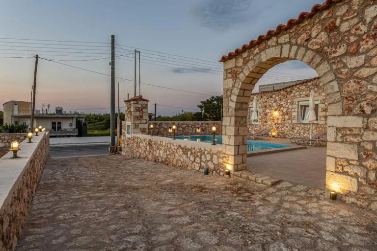 - un bâtiment en pierre avec une arche à côté d'une piscine dans l'établissement Villa Argyro, à Kolymbari