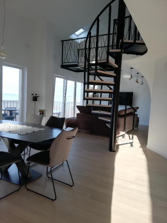 a living room with a table and a spiral staircase at Apartmani Zora in Primošten