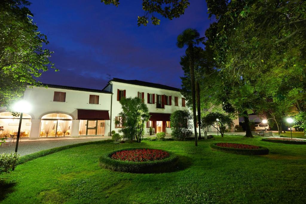 - un grand bâtiment blanc avec un jardin la nuit dans l'établissement Hotel Villa Patriarca, à Mirano