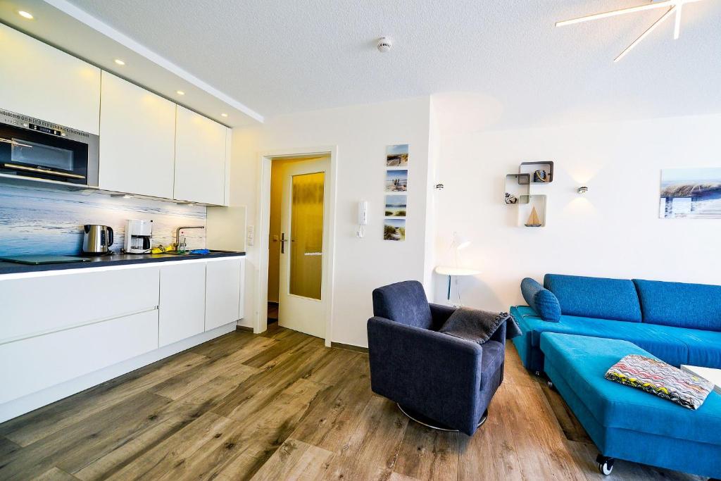 een woonkamer met een blauwe bank en een keuken bij Haus Frische Brise 0707 in Cuxhaven