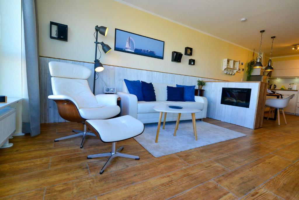 uma sala de estar com um sofá, cadeiras e uma mesa em Haus Frische Brise 1210 em Cuxhaven