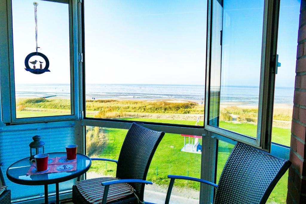 einen Tisch und Stühle in einem Zimmer mit Meerblick in der Unterkunft Haus Horizont HZ09 in Cuxhaven