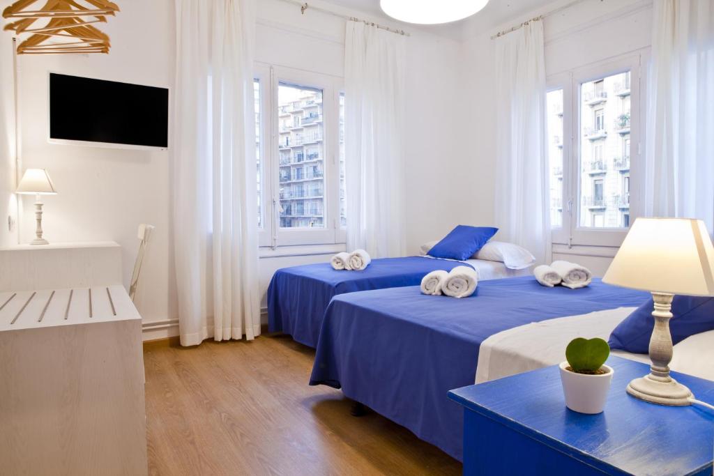 two beds in a room with two windows at Blue Barcelona in Barcelona