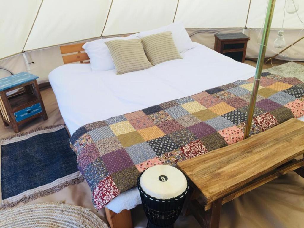 una camera con un letto con una trapunta e un tavolo di Glór na d'Tonnta Glamping a Sligo