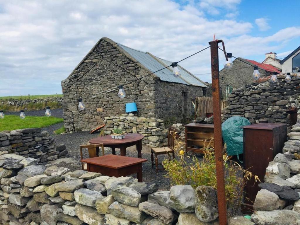 una casa in pietra con tavolo e muro di pietra di Glór na d'Tonnta Glamping a Sligo