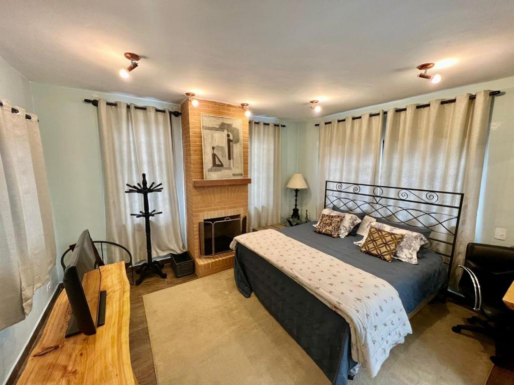 Un dormitorio con una cama y una chimenea. en Cabana Toscana, en Campos do Jordão