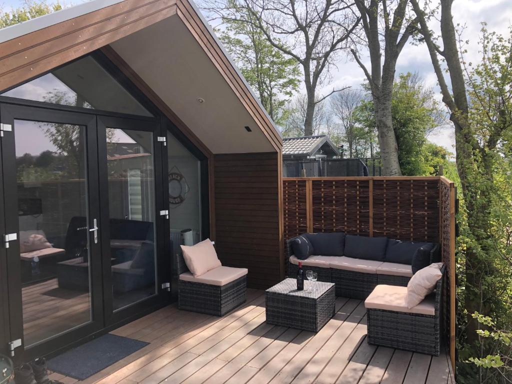 eine Terrasse mit einem Sofa und Stühlen auf einer Terrasse in der Unterkunft Luxe vrijstaande chalet voor gezinnen en stellen in Elahuizen