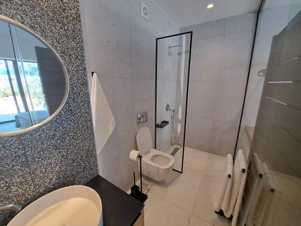 a bathroom with a toilet and a shower with a mirror at Courtyard Luxury Suites “ APOSTOLOS” in Pefki