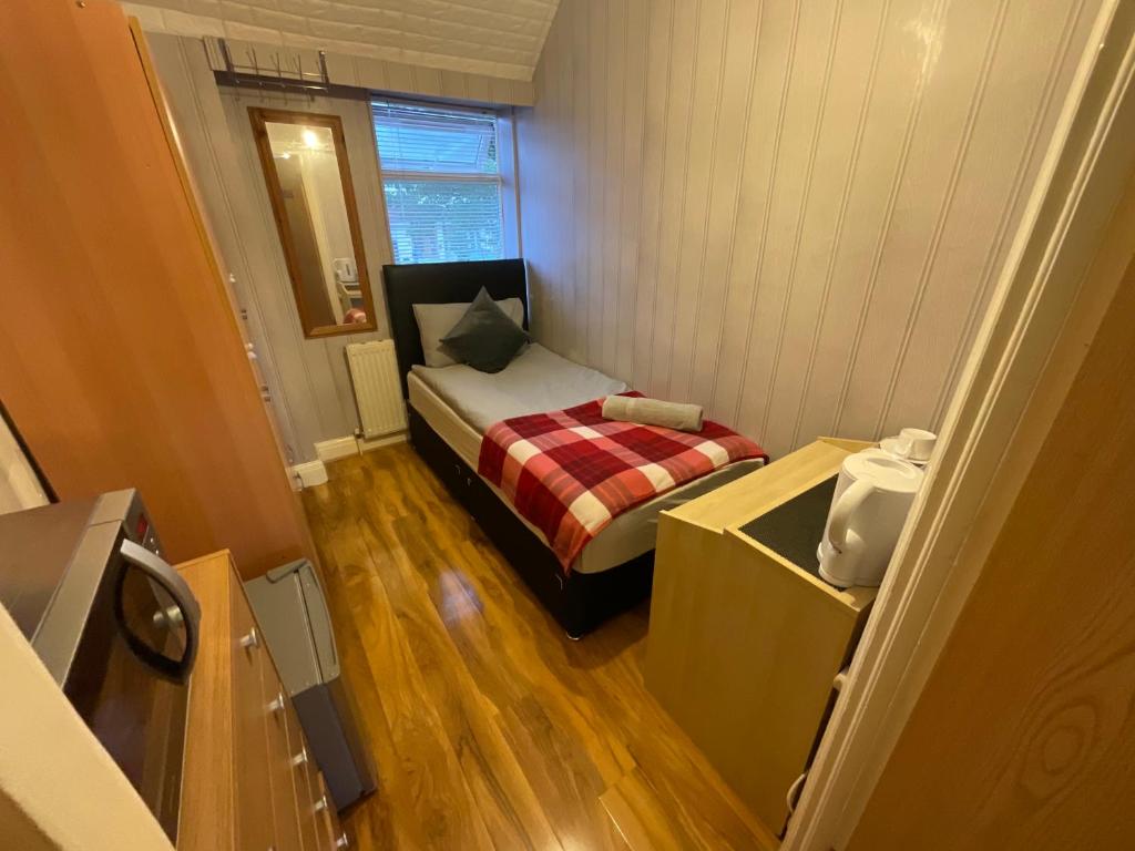 Cette petite chambre comprend un lit et une fenêtre. dans l'établissement Comfortable single room in Family home, Heathrow airport, à Northolt