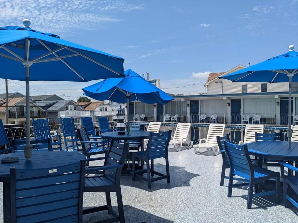 patio z niebieskimi stołami i krzesłami z niebieskimi parasolami w obiekcie Tide Winds Motel w mieście Wildwood