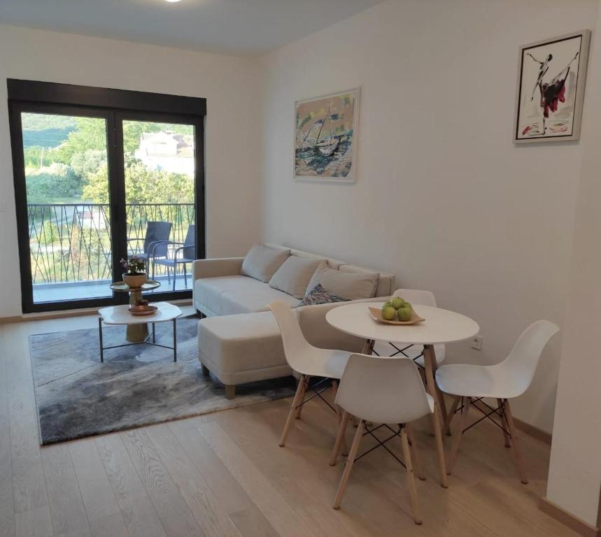 a living room with a couch and a table and chairs at Harmony Tivat Apartment in Tivat