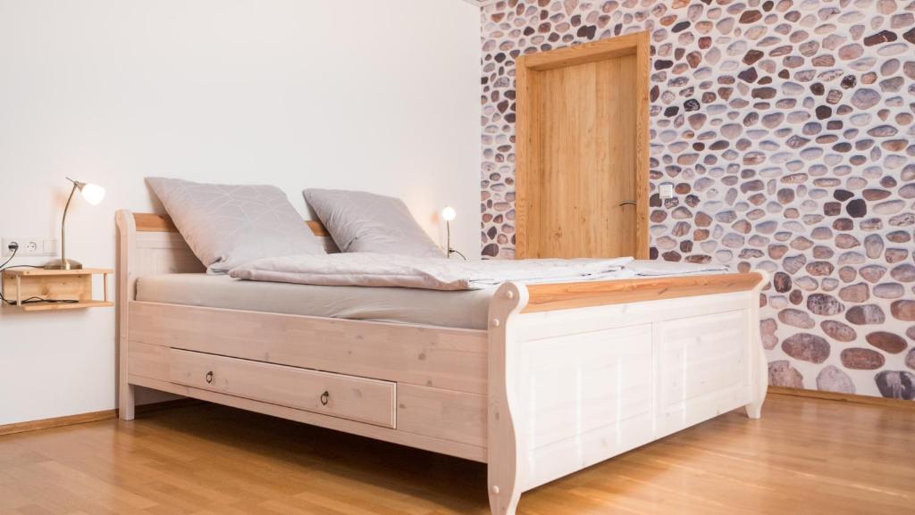 a wooden bed in a room with a brick wall at PfalzZeit in Weisenheim am Berg