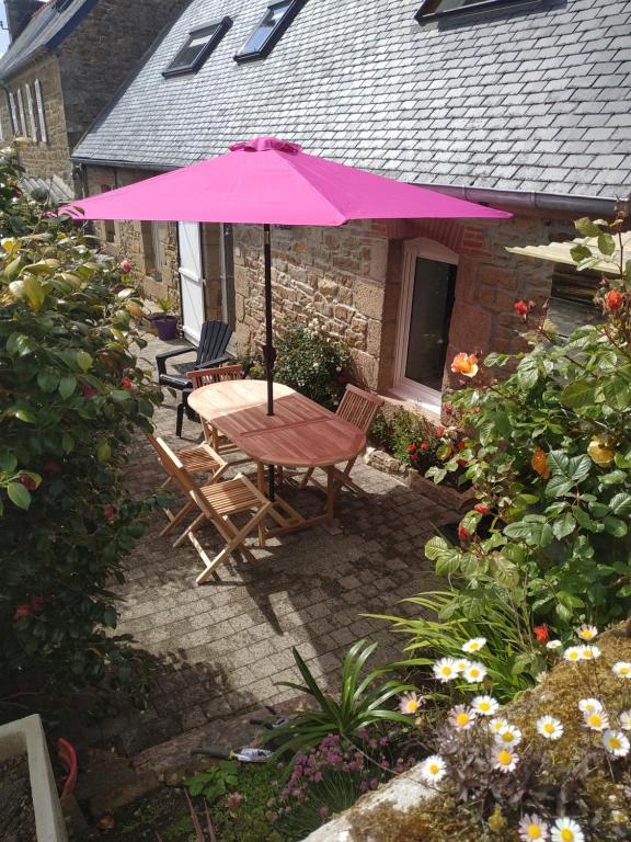 un tavolo e sedie sotto un ombrellone rosa in un cortile di TI-ARMOR a Louannec