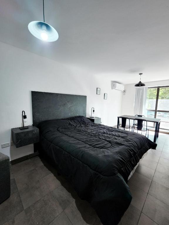 Un dormitorio con una gran cama negra y una mesa en CÓMODO Y LUMINOSO DEPARTAMENTO TEMPORARIO en Córdoba