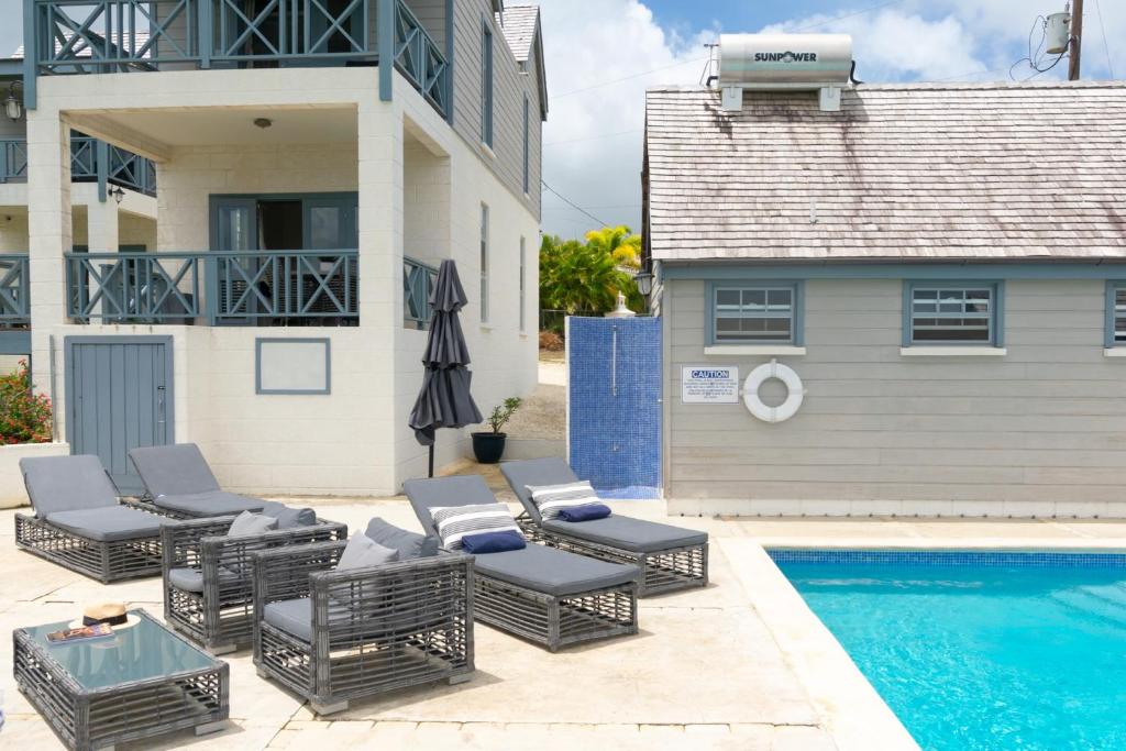 a patio with chairs and a pool and a house at West Rock Villas in Saint James