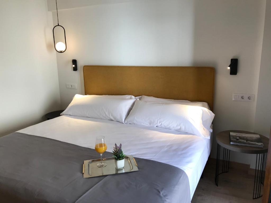 HOTEL MONTE PERDIDO في بييلسا: سرير مع صينية مع كوب من النبيذ