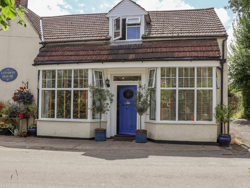 uma casa com uma porta azul e janelas em Little London em Battle