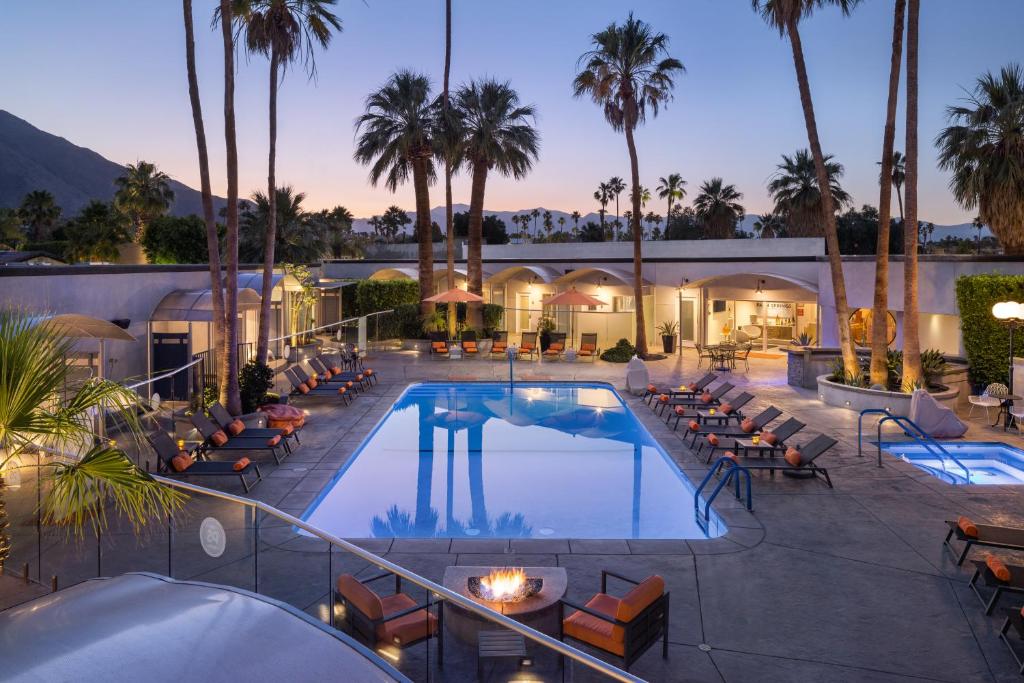 uma piscina do hotel com espreguiçadeiras e palmeiras em The Palm Springs Hotel em Palm Springs