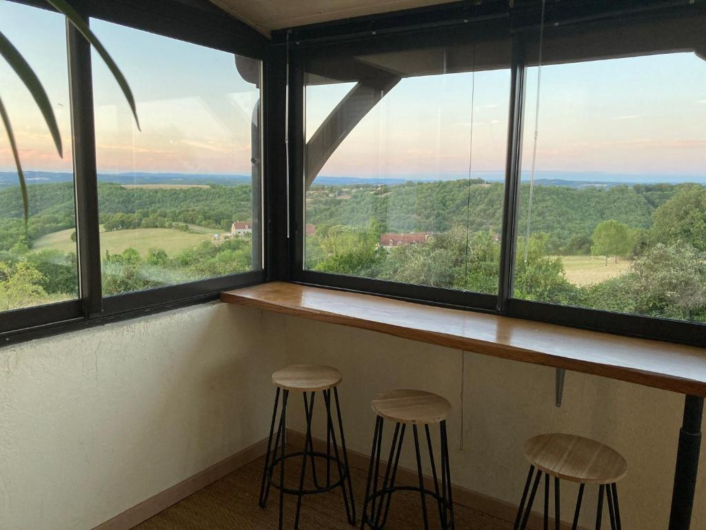 a bar with three stools in front of a window at Gîte "le haut des Poujades" in Reilhaguet