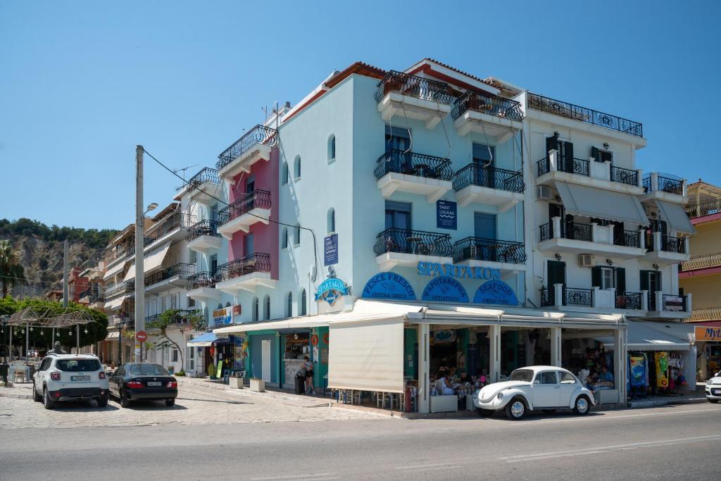 a building with cars parked in front of a street at Saint Loukas Studios in Zakynthos