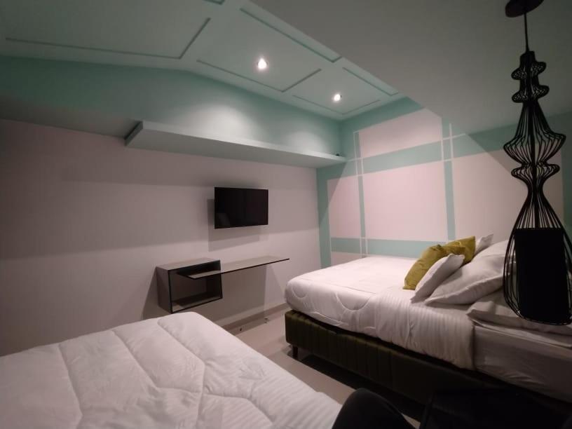 a bedroom with two beds and a tv on the wall at Home Mark Casa Boutique in Paipa
