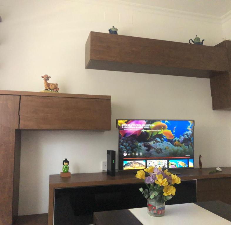 ein Wohnzimmer mit einem TV und einem Schreibtisch mit Blumen in der Unterkunft Casa la Torre in Cambados