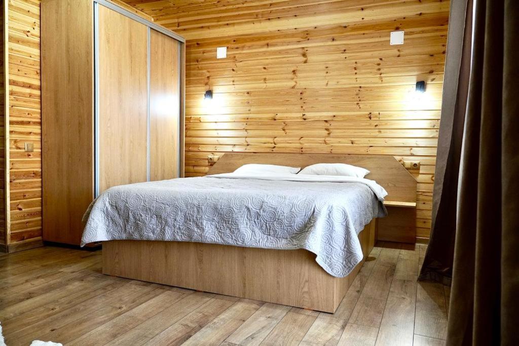 ein Schlafzimmer mit einem Bett in einer Holzwand in der Unterkunft Casa Felice in Braşov