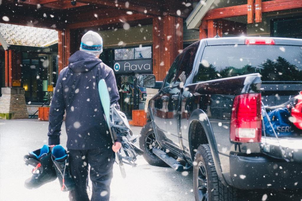 a person walking past a truck in the snow at Aava Whistler Hotel in Whistler