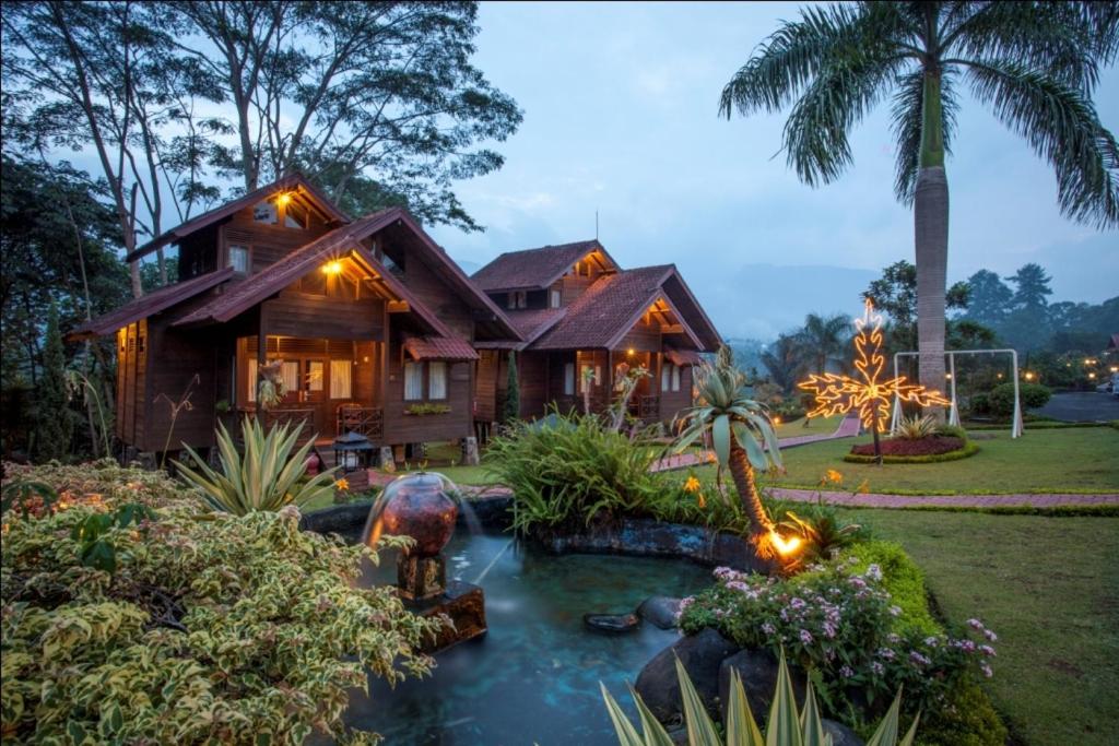 ein Haus mit einem Teich davor in der Unterkunft Citra Cikopo Hotel & Family Cottages in Puncak