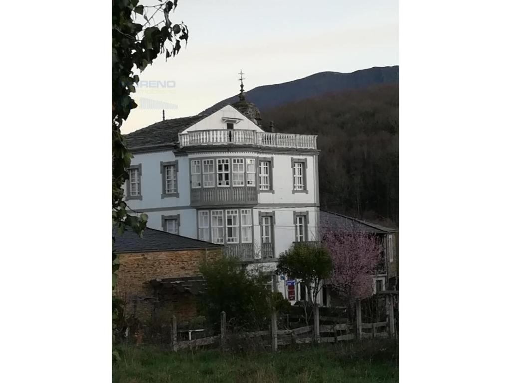 a large white house with a balcony on top of it at Pension Casa Simon in Tríacastela