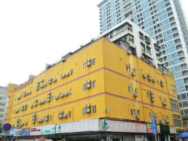 a yellow building in front of some tall buildings at 7Days Inn Zhuhai Jida Zhongdian Mansion in Zhuhai