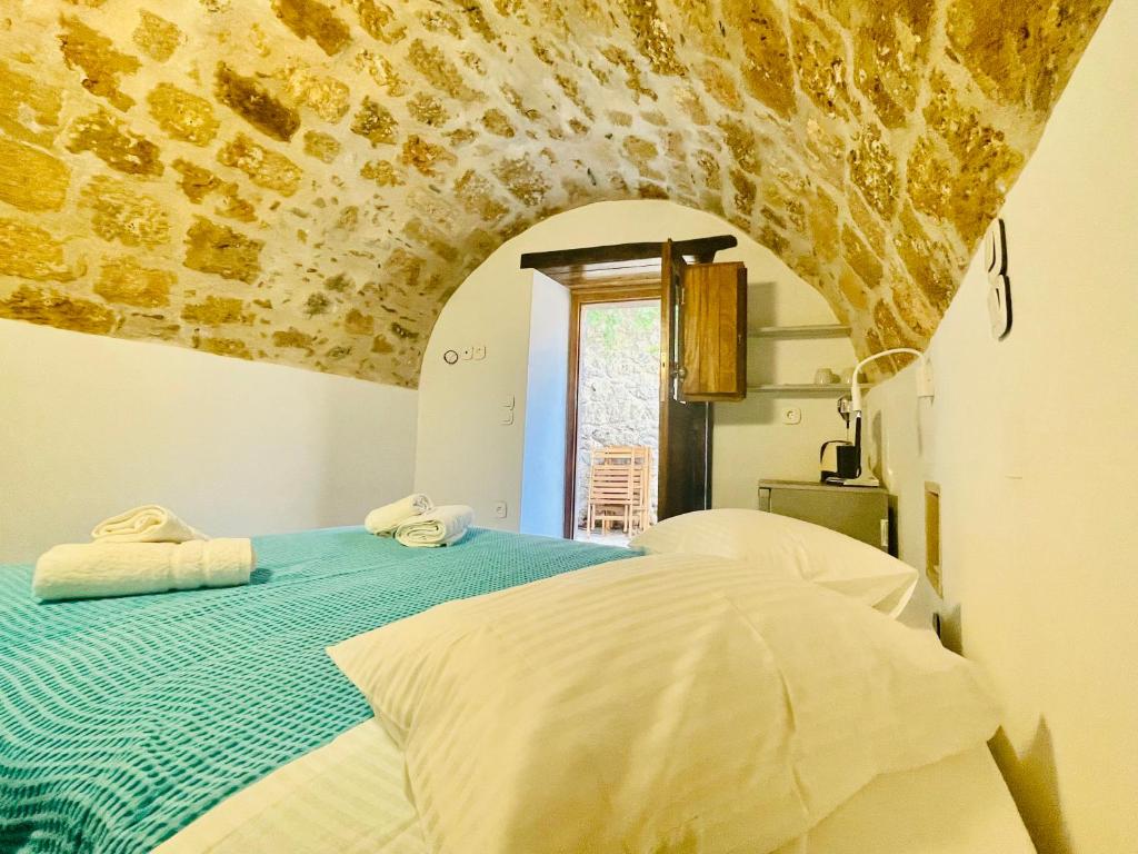 a bedroom with a bed with a stone wall at Vecchia Casa kamara in Monemvasia