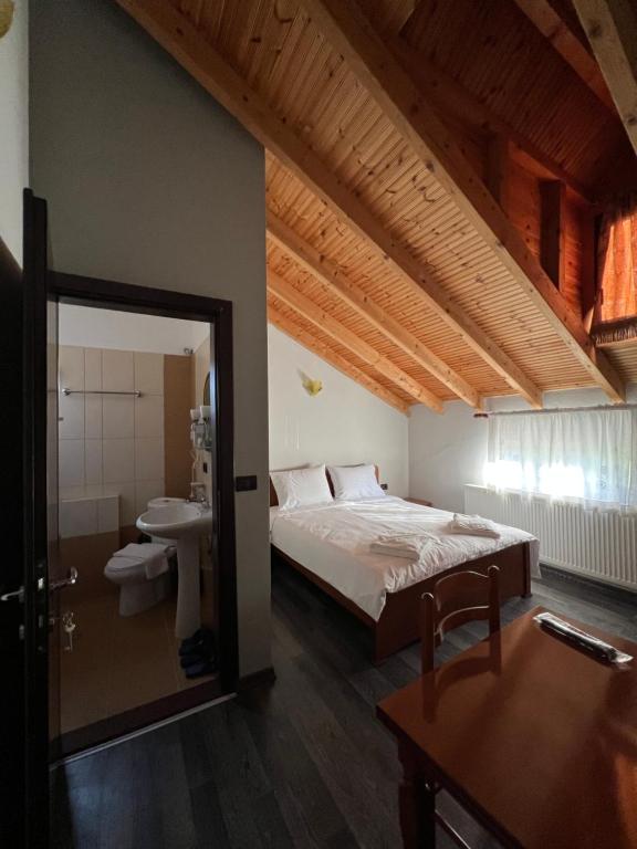 ein Schlafzimmer mit einem Bett und ein Badezimmer mit einem Waschbecken in der Unterkunft Vila Mata in Voskopoja