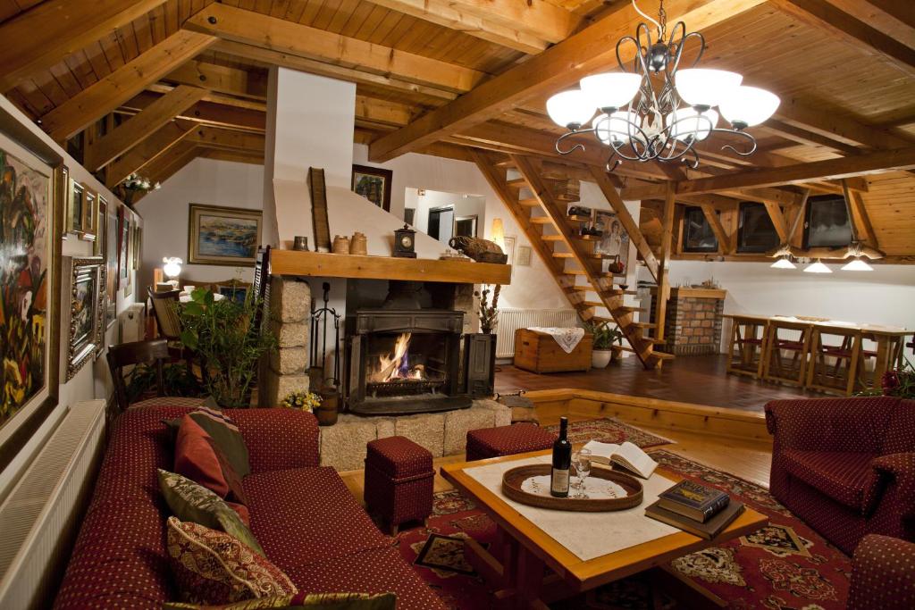a living room with a fireplace and a table and chairs at Villa Đurić Superior in Zlatibor