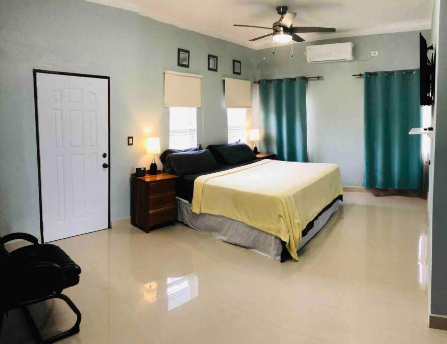 1 dormitorio con 1 cama y ventilador de techo en The Ansen Place, en Belmopan