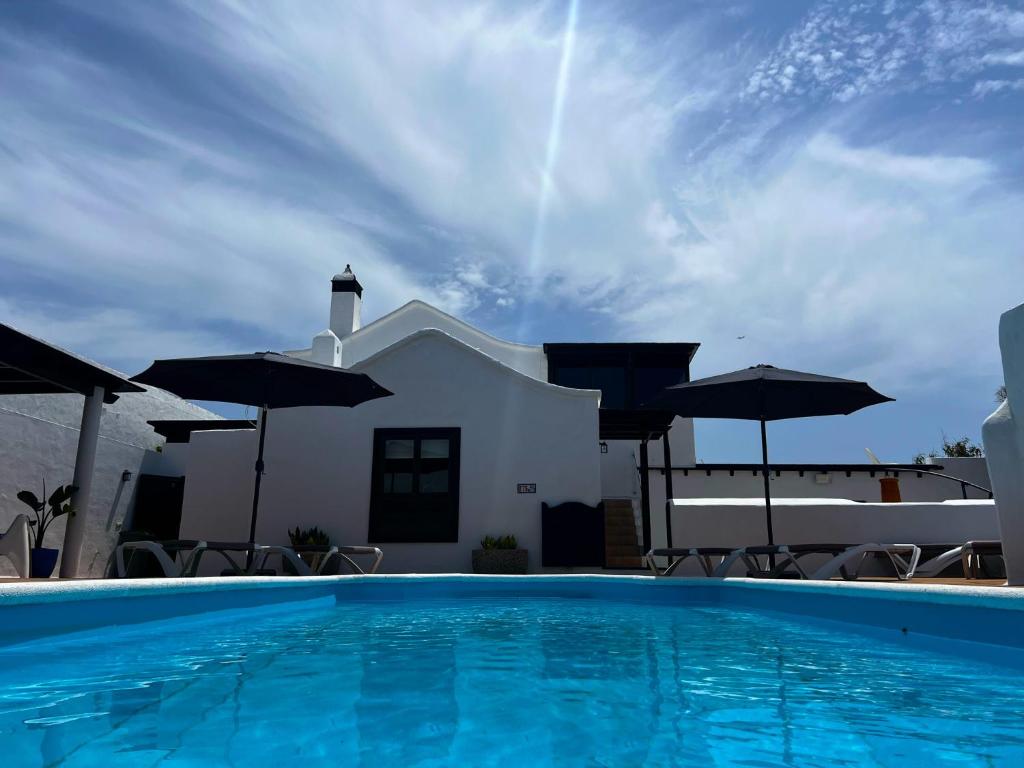 a swimming pool with umbrellas in front of a house at Nazaret Villa with heated pool in Nazaret