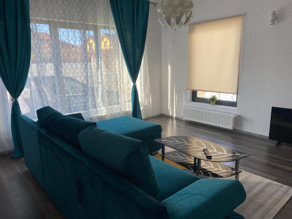 uma sala de estar com dois sofás azuis e uma mesa de vidro em DA Residence em Otopeni