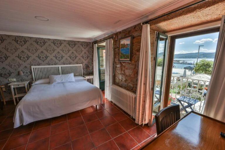 a bedroom with a bed and a large window at Hotel Puerto Arnela in Camariñas