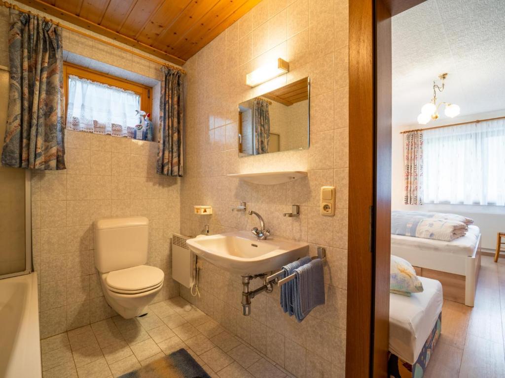a bathroom with a toilet and a sink and a bed at Apartment Claudia in Vandans