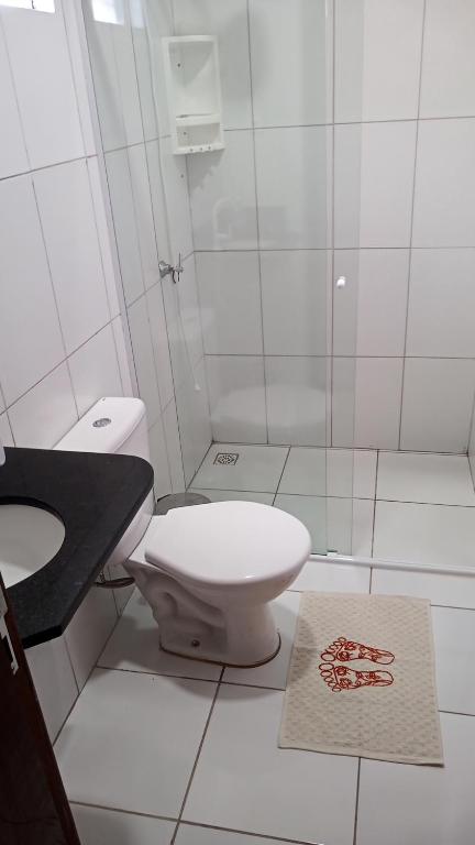 a white bathroom with a toilet and a sink at Casa de temporada 02 -Chalé Portal do Paraíso in Santo Amaro