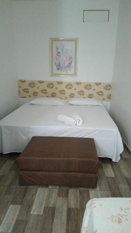 a hotel room with a bed with a brown ottoman at Hospedaria Ilhéus 04 in Ilhéus