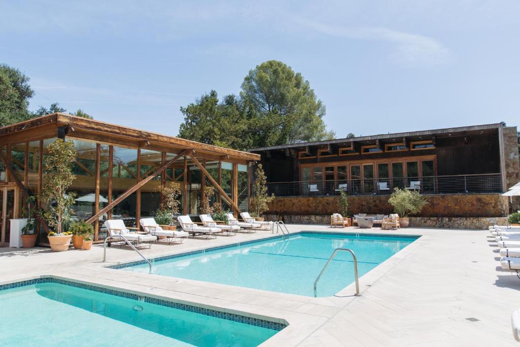 a swimming pool with chairs and a building at Calamigos Guest Ranch and Beach Club in Malibu
