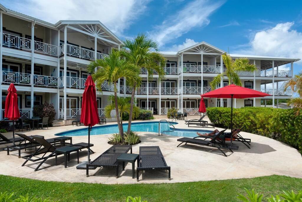 un complejo con piscina, sillas y sombrillas en Private Condo on the West Coast of Barbados, en Saint James