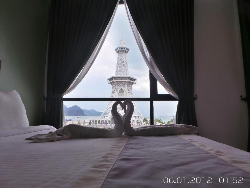 Uma mulher deitada numa cama em frente à Torre Eiffel. em We Hotel Langkawi em Kuah