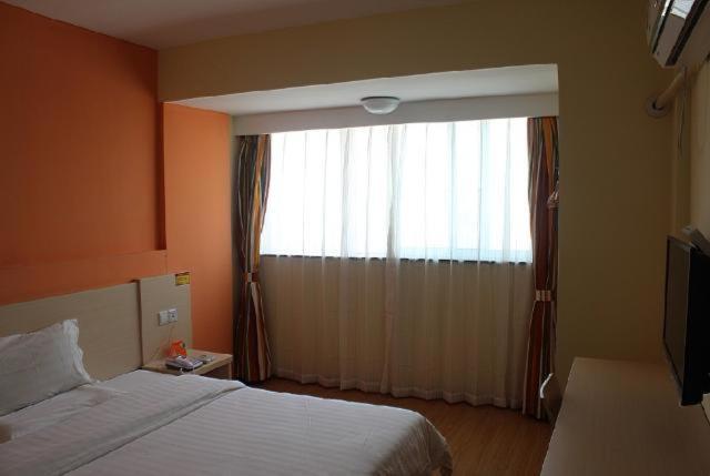 a bedroom with a bed and a large window at 7Days Inn Hangzhou Xiasha in Hangzhou