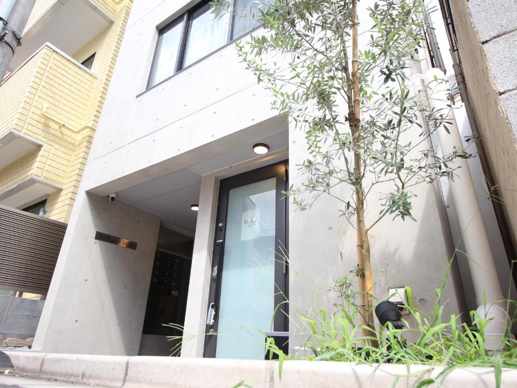 Shinjuku area Industria Wind apartment Walk 6min To Station في طوكيو: مبنى امامه شجرة